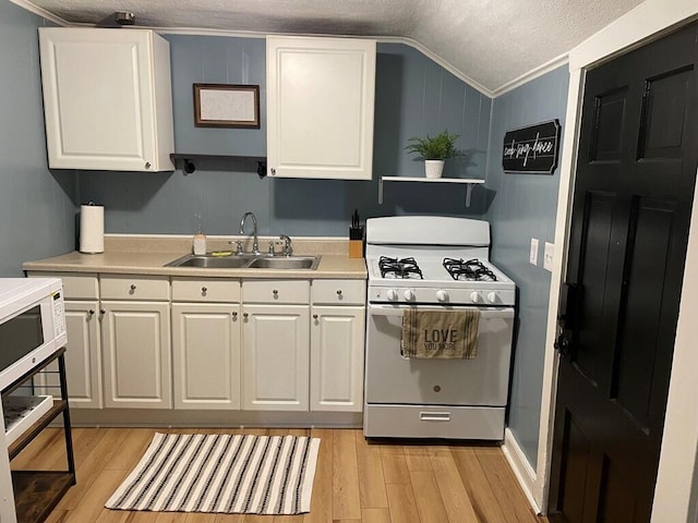 kitchen featuring lofted ceiling, sink, white cabinets, ornamental molding, and white appliances