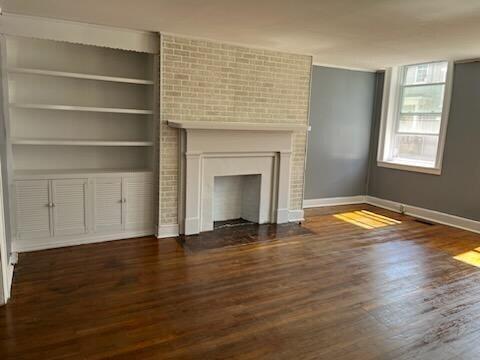 unfurnished living room with built in shelves, a fireplace, and dark hardwood / wood-style floors