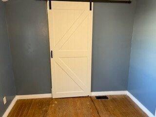 interior space with a barn door and dark hardwood / wood-style floors