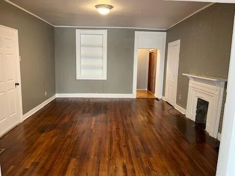 unfurnished living room with dark hardwood / wood-style flooring and crown molding