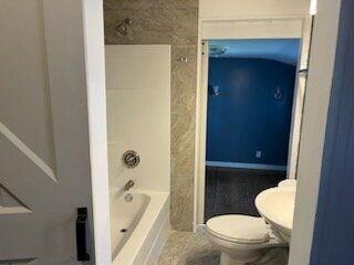 bathroom featuring shower / bathtub combination and toilet