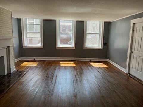 interior space featuring crown molding, a fireplace, dark hardwood / wood-style floors, and a healthy amount of sunlight