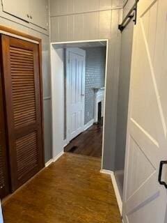 corridor with a barn door and hardwood / wood-style floors