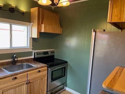 kitchen featuring stainless steel appliances, sink, a notable chandelier, and custom range hood