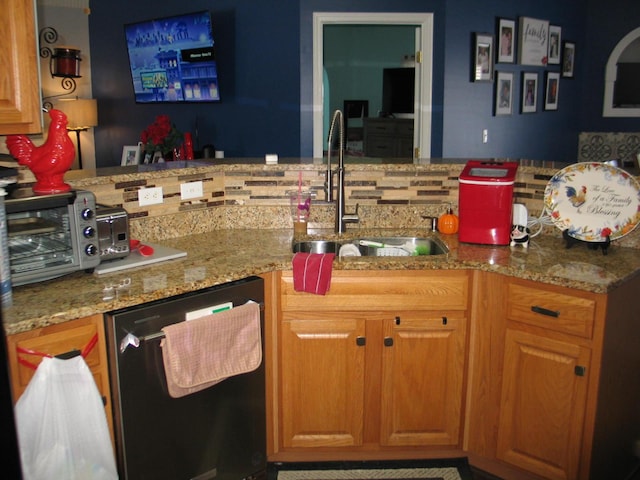 kitchen with light stone counters, sink, and stainless steel dishwasher