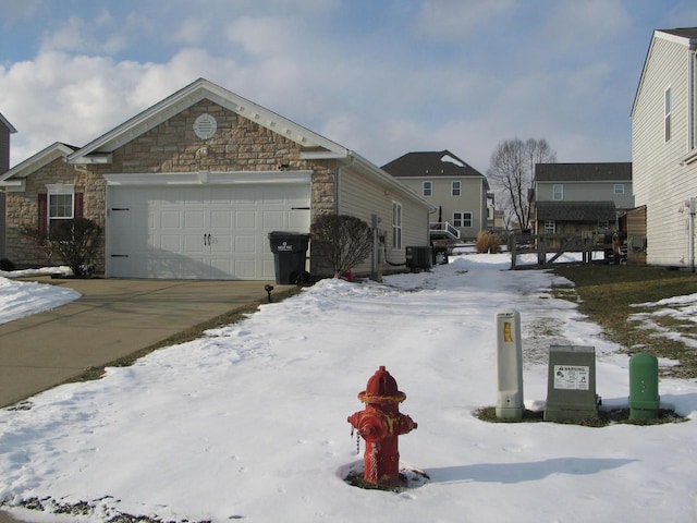 view of snowy exterior with central air condition unit and a garage