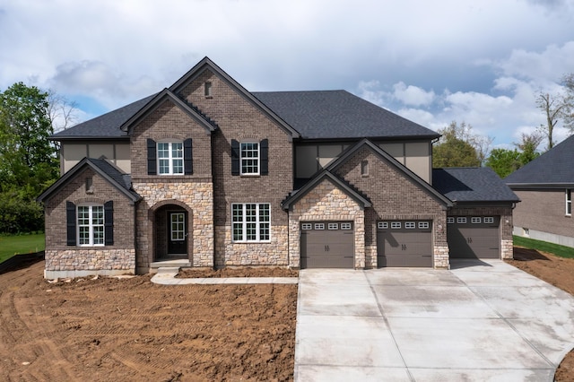 view of front facade with a garage, concrete driveway, stone siding, roof with shingles, and stucco siding