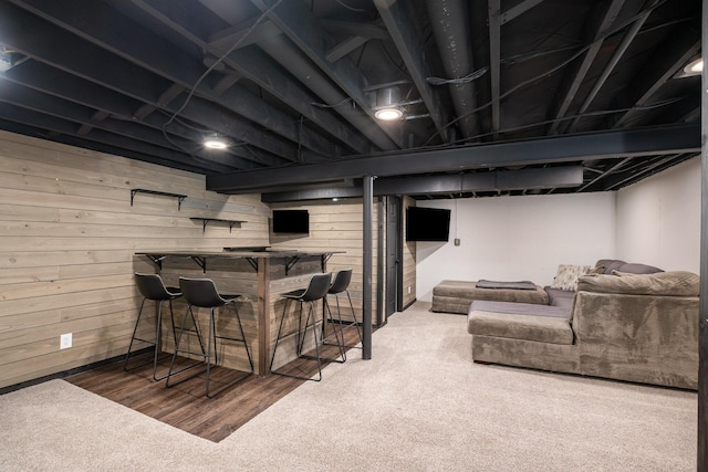 basement featuring indoor bar, carpet, and wood walls