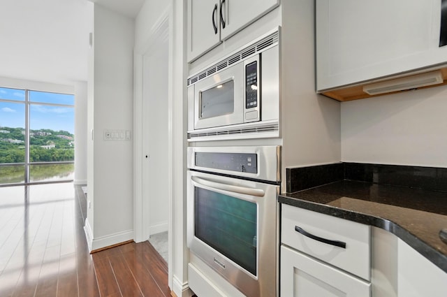 400 Riverboat Row Unit 605, Newport, KY 41071 - kitchen with appliances with stainless steel finishes, dark wood finished floors, dark stone counters, baseboards, and white cabinets