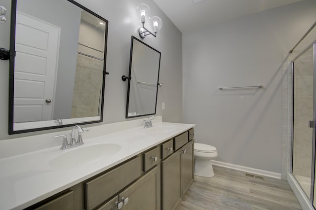 bathroom featuring toilet, hardwood / wood-style floors, vanity, and walk in shower