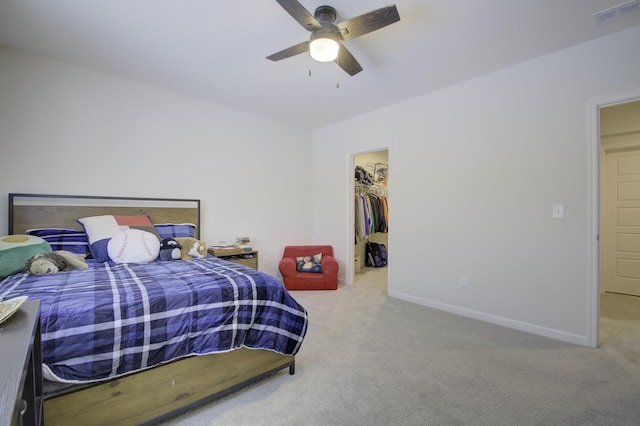 bedroom with a walk in closet, light carpet, ceiling fan, and a closet