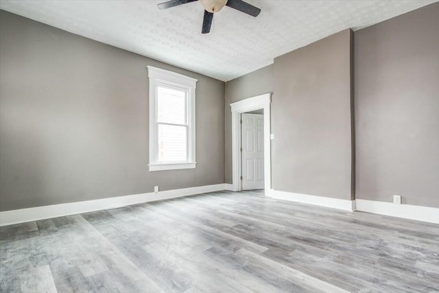 empty room featuring ceiling fan, light hardwood / wood-style flooring, and a textured ceiling