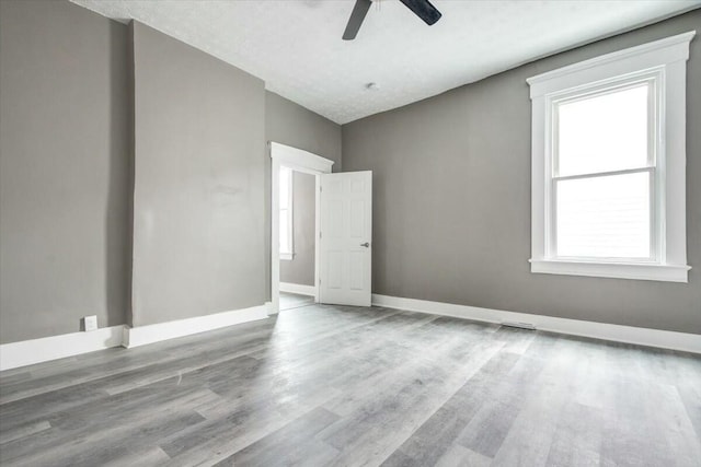 empty room featuring light hardwood / wood-style flooring, a textured ceiling, plenty of natural light, and ceiling fan