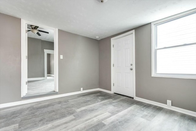 unfurnished room featuring ceiling fan, a textured ceiling, and light wood-type flooring