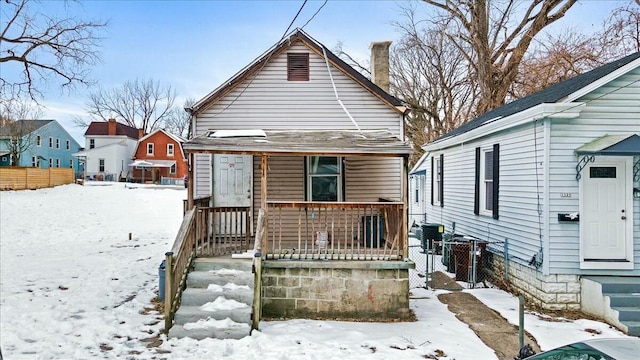 snow covered rear of property with covered porch