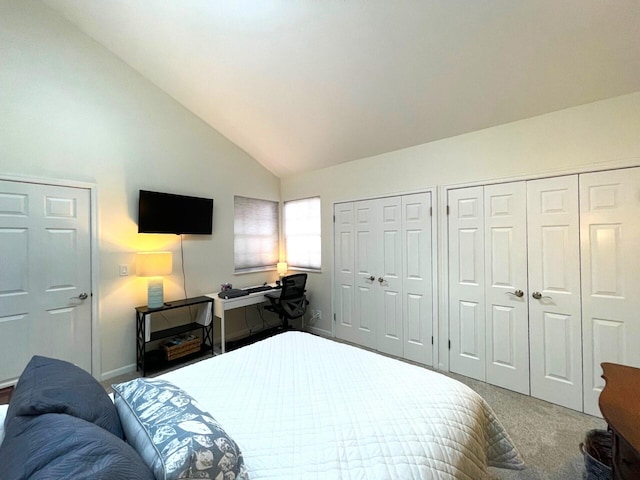 carpeted bedroom featuring multiple closets and high vaulted ceiling