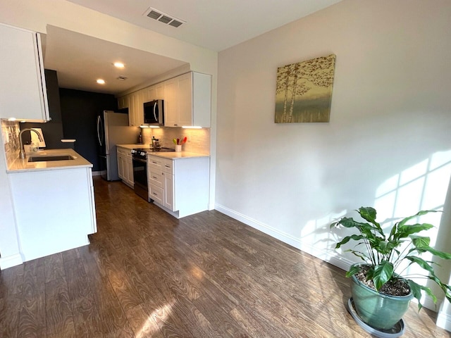 kitchen with sink, stainless steel appliances, tasteful backsplash, white cabinets, and dark hardwood / wood-style flooring