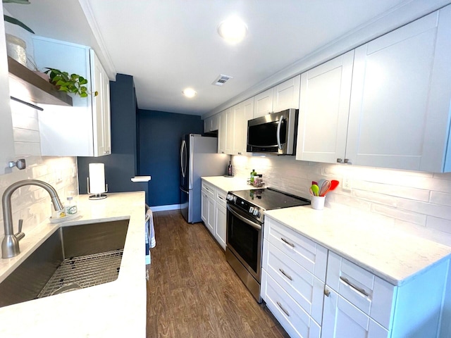 kitchen featuring appliances with stainless steel finishes, tasteful backsplash, white cabinetry, sink, and dark hardwood / wood-style flooring