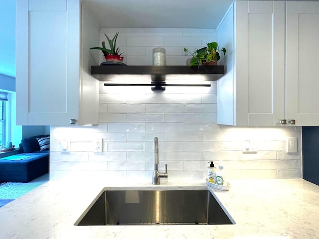 kitchen with light stone counters, sink, and white cabinets