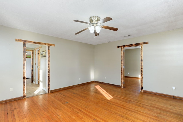 spare room with a textured ceiling, light hardwood / wood-style flooring, and ceiling fan