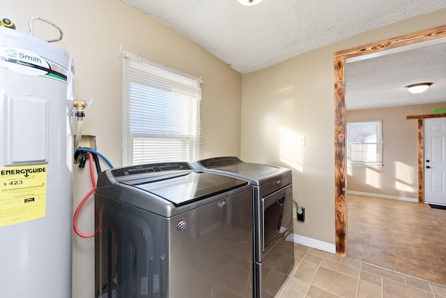 laundry room featuring washing machine and clothes dryer, light tile patterned floors, a textured ceiling, and water heater