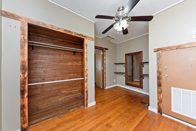 unfurnished bedroom featuring ceiling fan, a textured ceiling, a closet, and light wood-type flooring