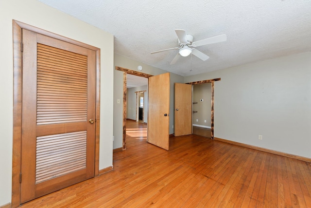 unfurnished bedroom featuring light wood-type flooring, a textured ceiling, a closet, and ceiling fan