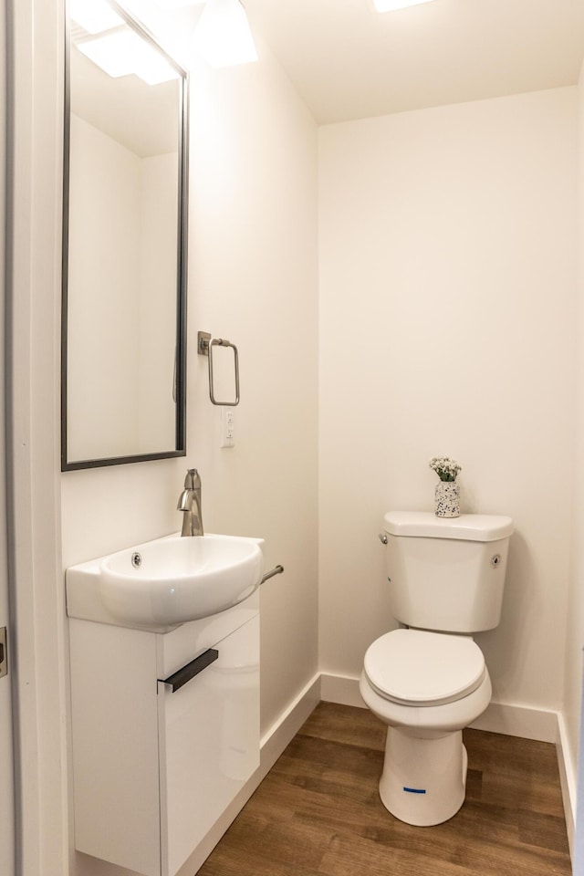 bathroom with hardwood / wood-style flooring, vanity, and toilet