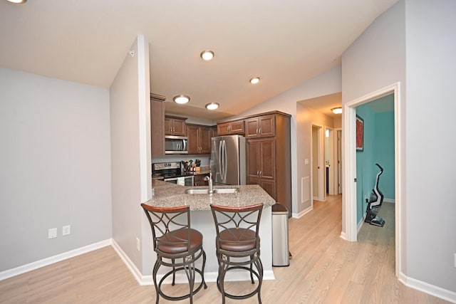 kitchen featuring lofted ceiling, sink, a kitchen breakfast bar, kitchen peninsula, and stainless steel appliances