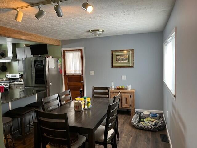 dining area with a textured ceiling and dark hardwood / wood-style flooring