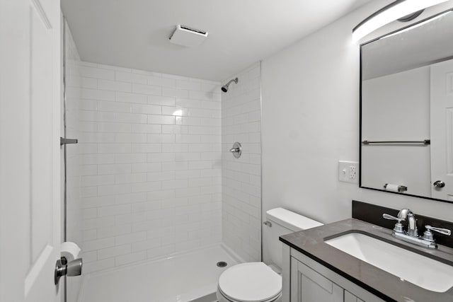 bathroom with vanity, a tile shower, and toilet