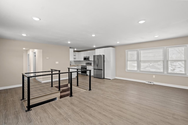 kitchen with white cabinetry, appliances with stainless steel finishes, sink, and light hardwood / wood-style floors