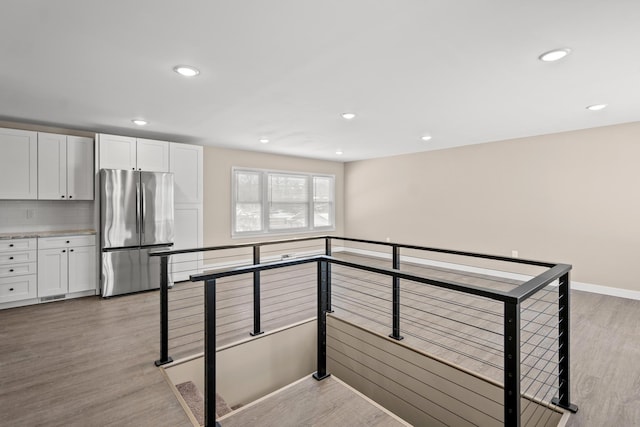 interior space with tasteful backsplash, white cabinets, stainless steel refrigerator, and light hardwood / wood-style floors