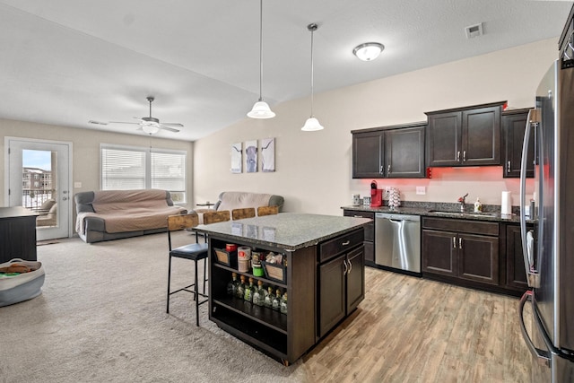 kitchen with dark brown cabinetry, stainless steel appliances, a center island, and sink