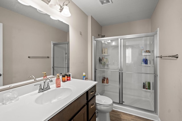 bathroom with wood-type flooring, toilet, an enclosed shower, and vanity