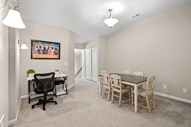 carpeted dining room featuring vaulted ceiling