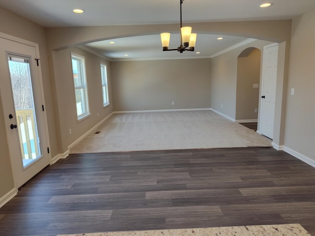 empty room featuring ornamental molding, dark hardwood / wood-style flooring, and a notable chandelier