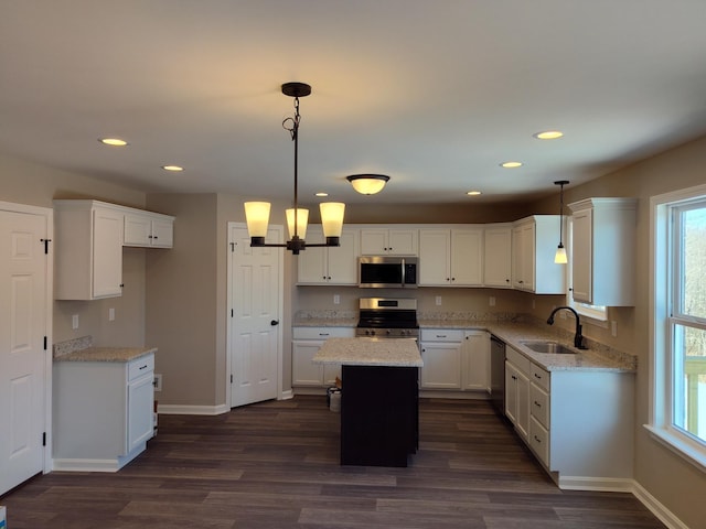 kitchen with pendant lighting, sink, white cabinetry, stainless steel appliances, and a kitchen island