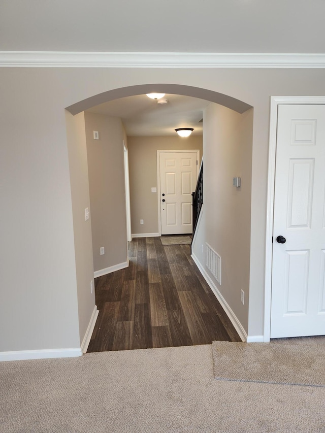 hallway with dark carpet and ornamental molding