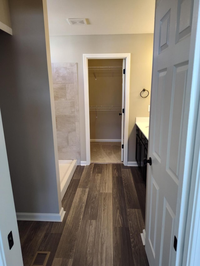 bathroom featuring hardwood / wood-style flooring, vanity, and a shower