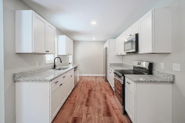 kitchen featuring light stone counters, appliances with stainless steel finishes, sink, and white cabinets