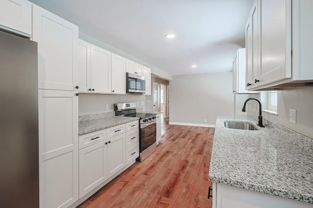 kitchen featuring sink, stainless steel appliances, white cabinets, and light stone countertops