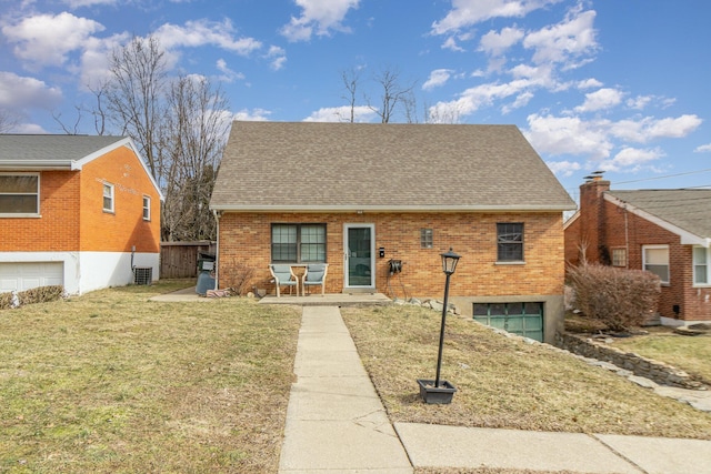 view of front facade with a garage, brick siding, a front lawn, and a shingled roof