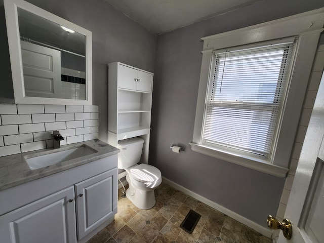 bathroom featuring vanity, toilet, and decorative backsplash