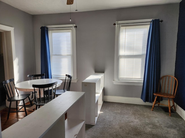 dining space featuring ceiling fan and dark colored carpet