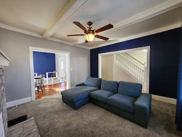 carpeted living room with ceiling fan, crown molding, a fireplace, and beamed ceiling