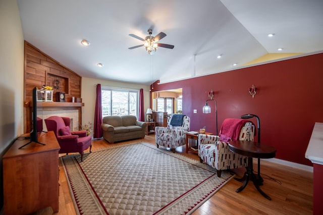 living room featuring wood-type flooring, ceiling fan, and vaulted ceiling