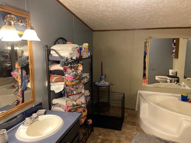 bathroom with vanity, a bath, crown molding, and a textured ceiling