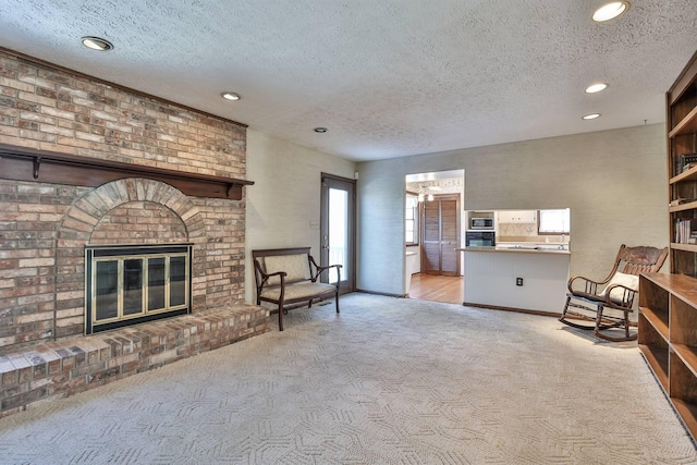 living area featuring a brick fireplace, light colored carpet, and a textured ceiling