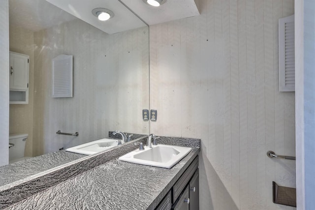 bathroom featuring vanity, wood walls, and toilet